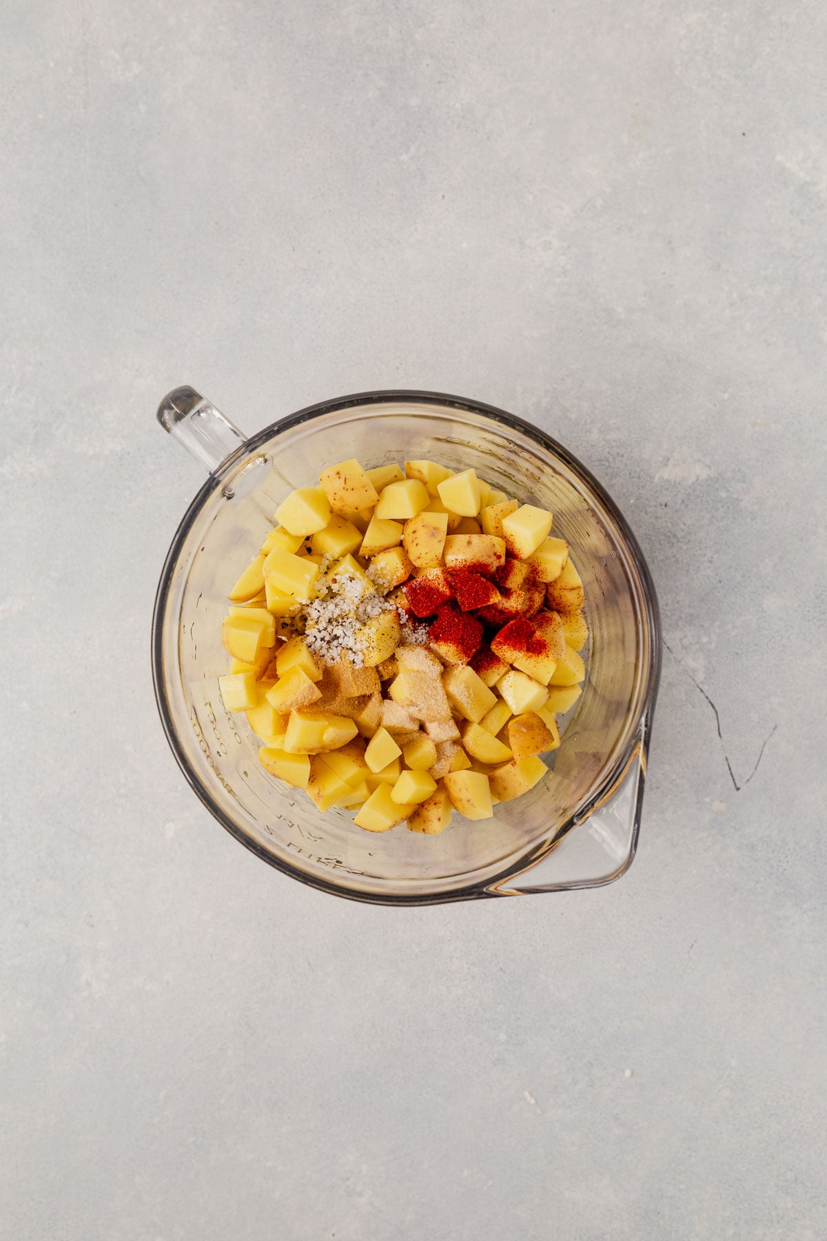 potatoes in a mixing bowl with seasoning