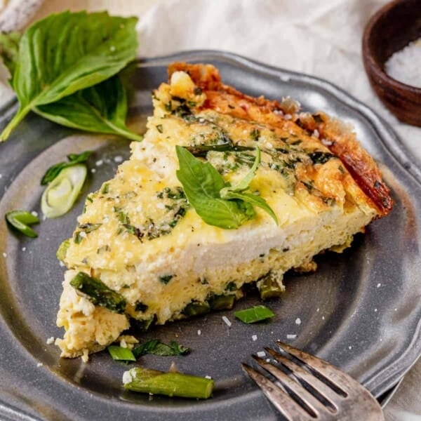 a piece of asparagus frittata on a plate with fresh basil