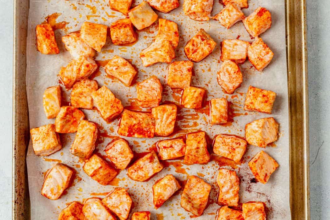 baked salmon cut into chunks on a baking sheet
