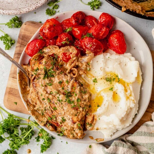 Boursin chicken on a plate with mashed potatoes and roasted cherry tomatoes