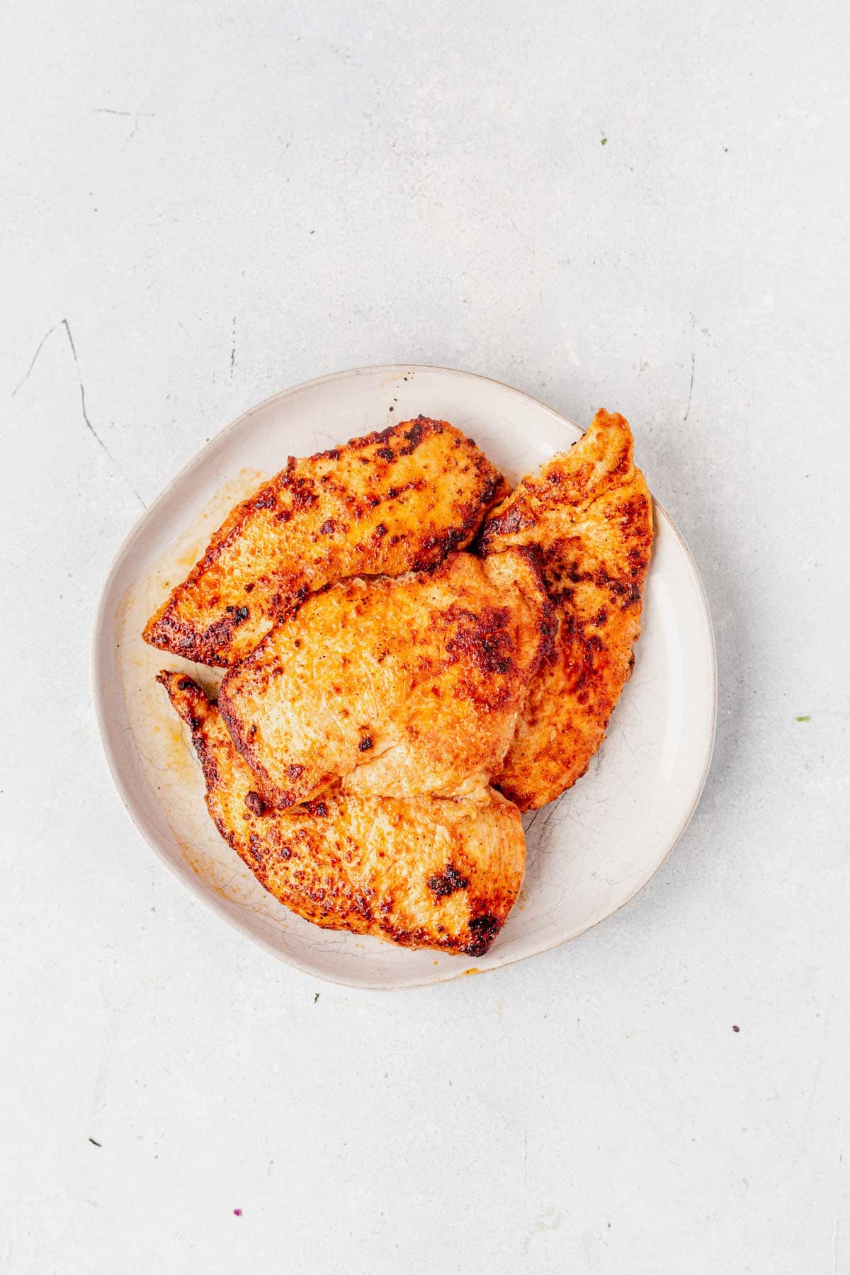 seared chicken breast for boursin chicken recipe on a white plate on the counter
