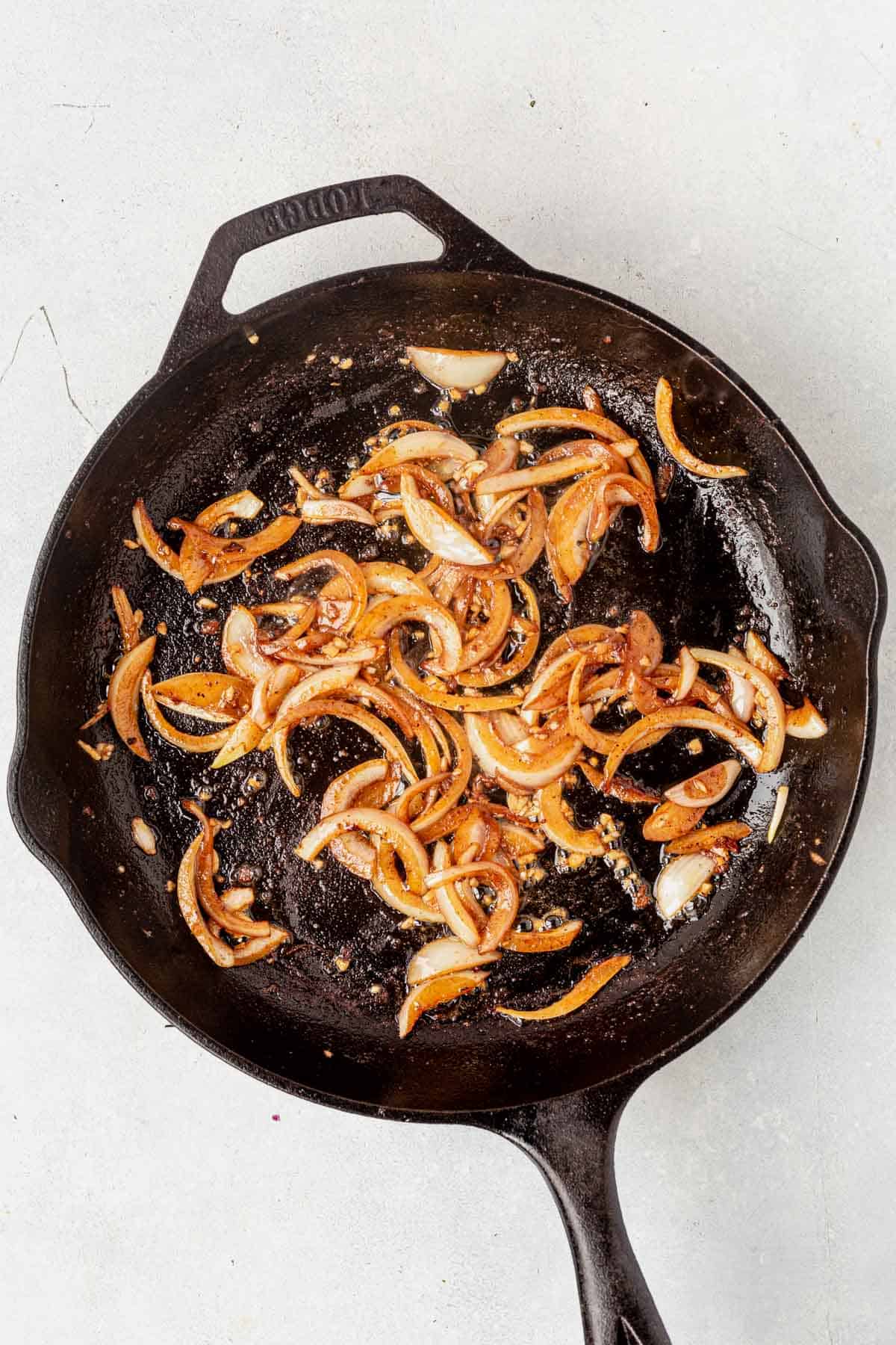 sauteed shallots in a cast iron pan on the stove as part of the boursin chicken recipe
