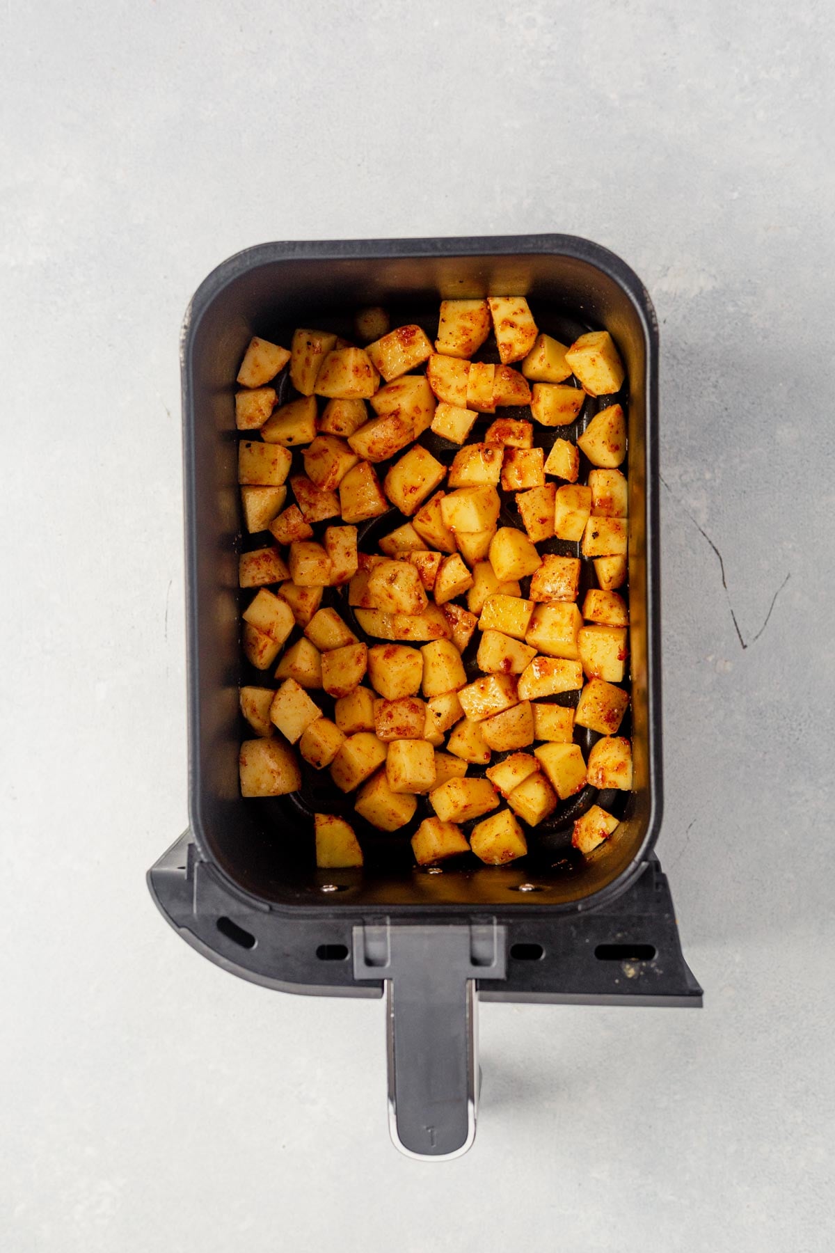 uncooked breakfast potatoes in an air fryer basket