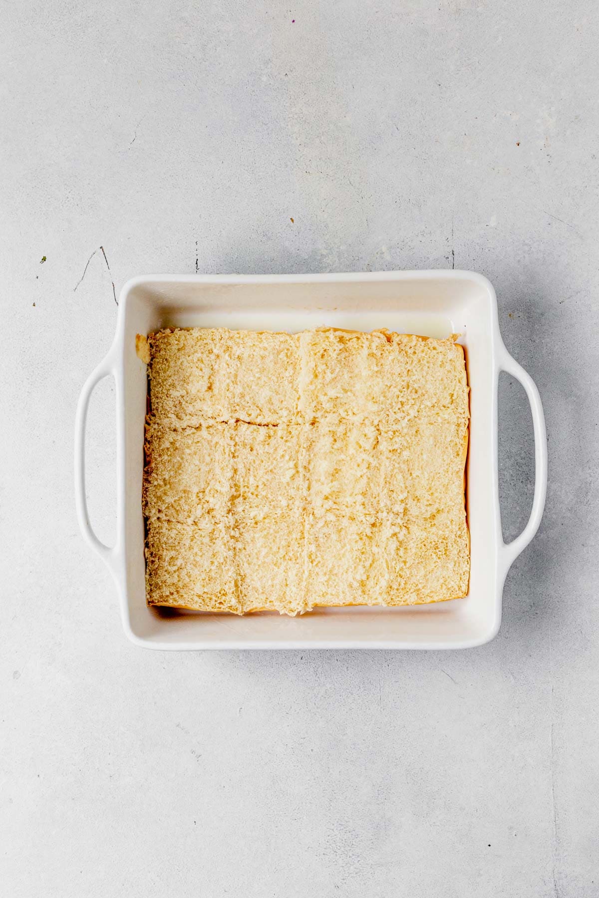 bottom of buns for breakfast sliders laid in a square baking pan on the counter