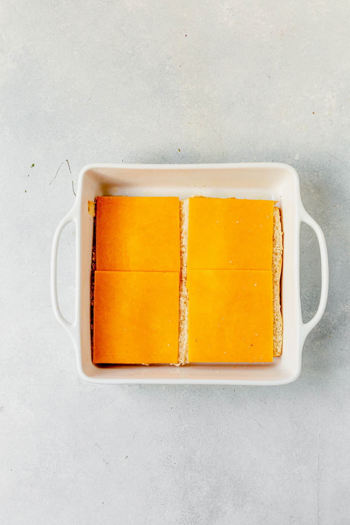 slices of cheese on top of eggs in breakfast sliders casserole dish