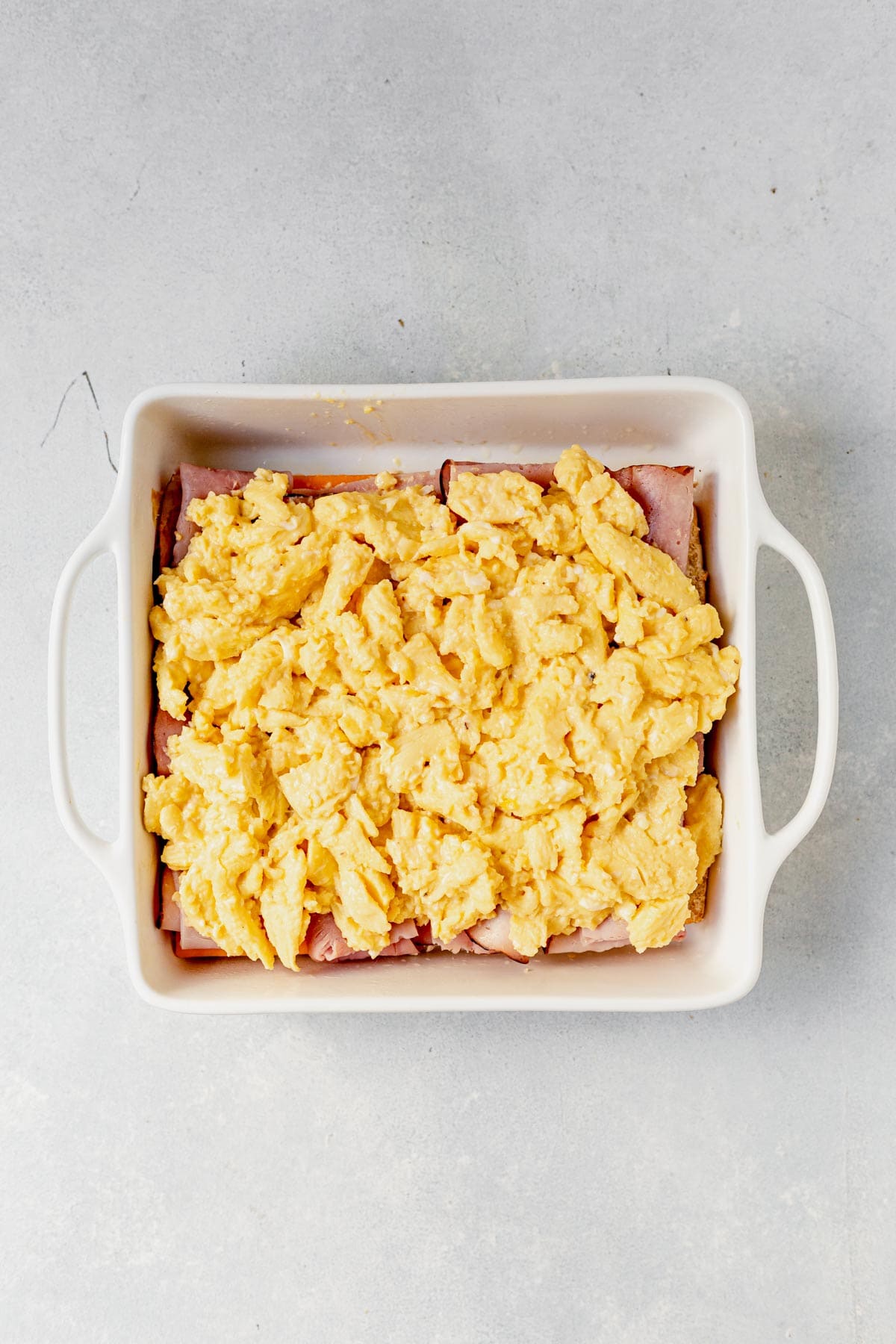 layer of scrambled eggs on top of sandwich slider bread in square baking pan