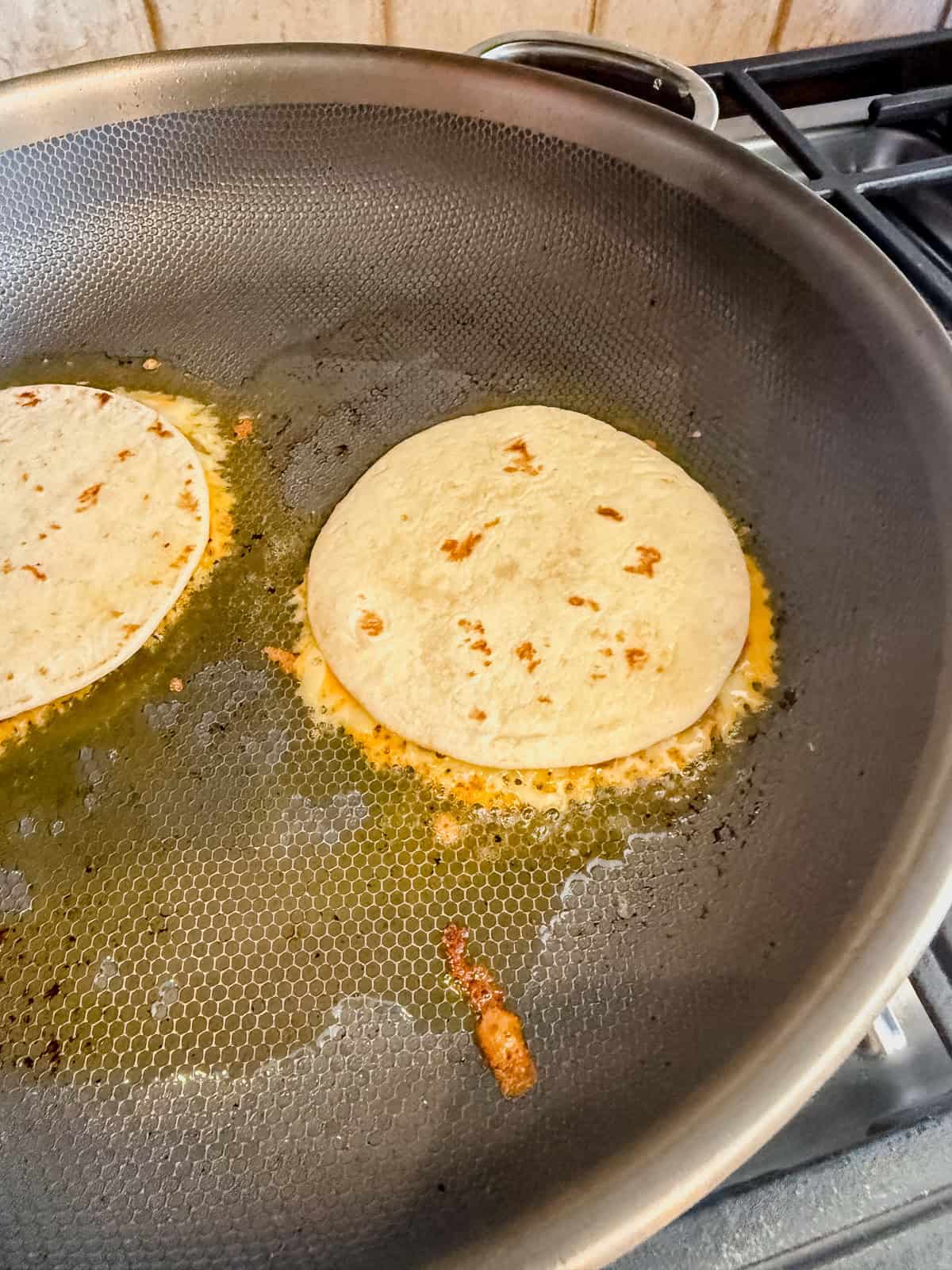 breakfast smash tacos cooking in a skillet.