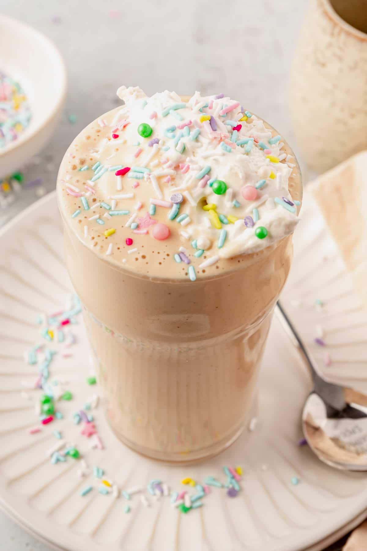 cake batter protein shake on a plate with whipped cream and sprinkles
