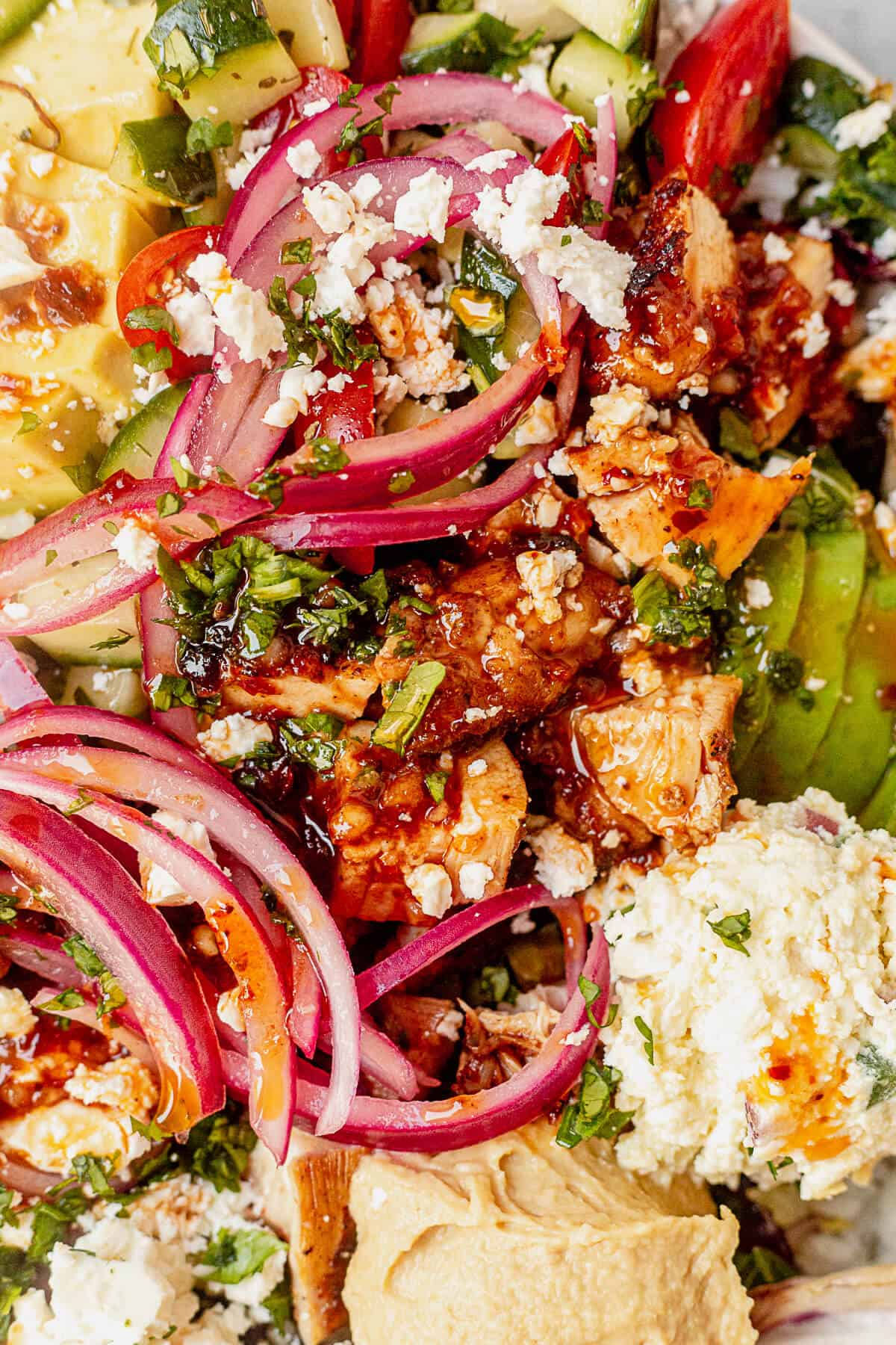 harissa vinaigrette on top of chicken, avocado, pickled onion, feta, and hummus
