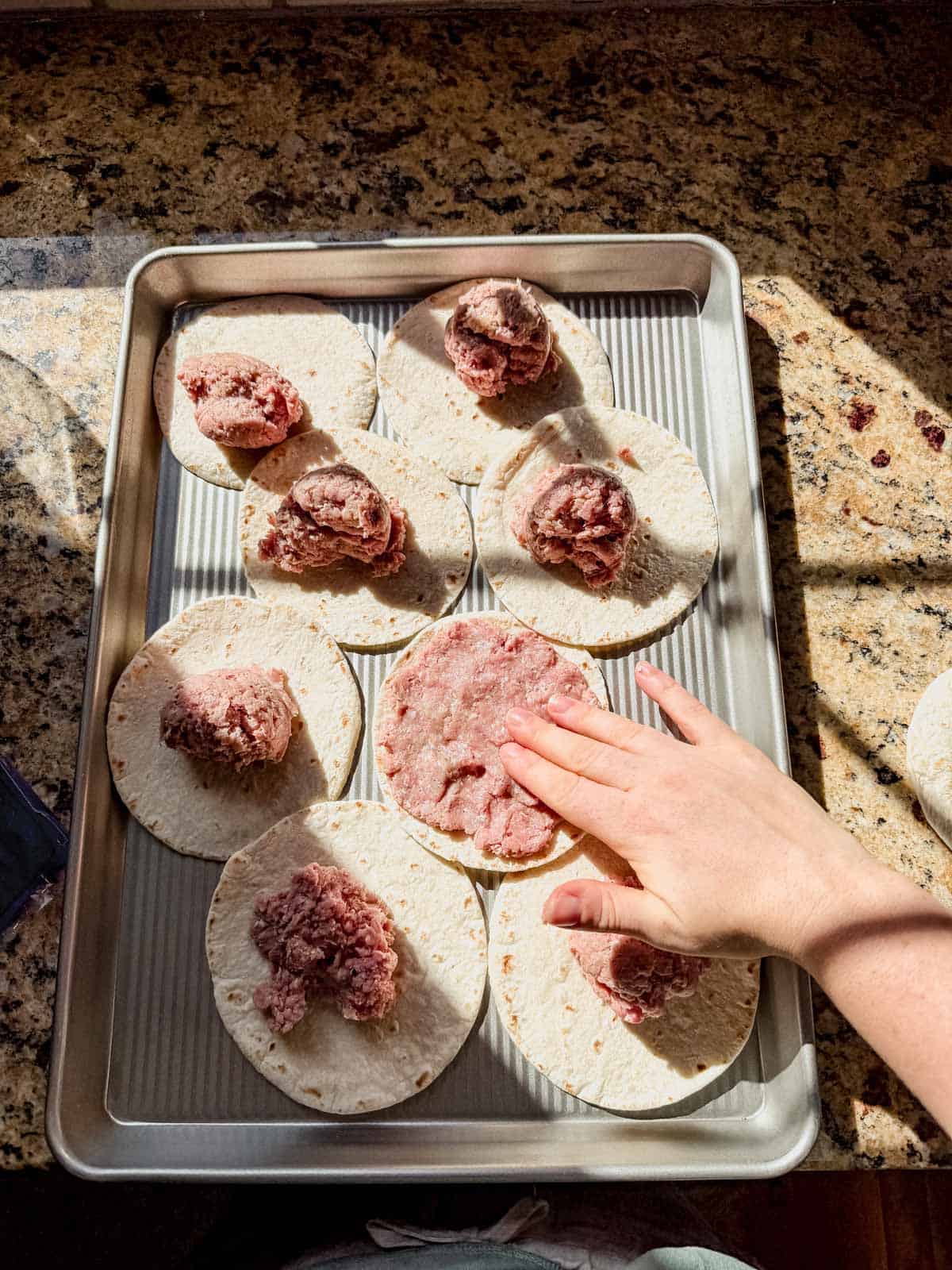 pressing ground chicken onto tortillas.