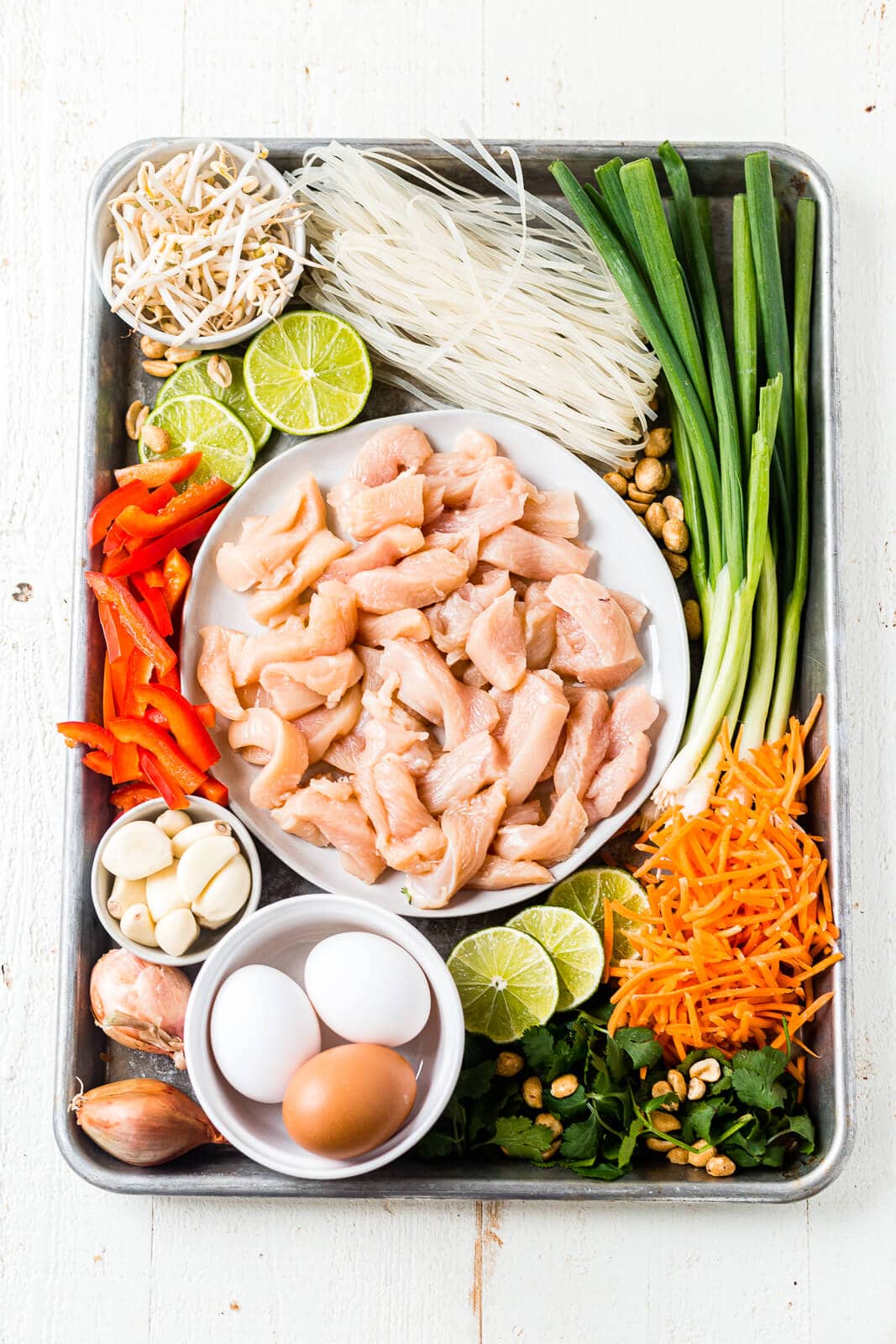 all of the ingredients for healthy chicken pad thai arranged on a sheet pan