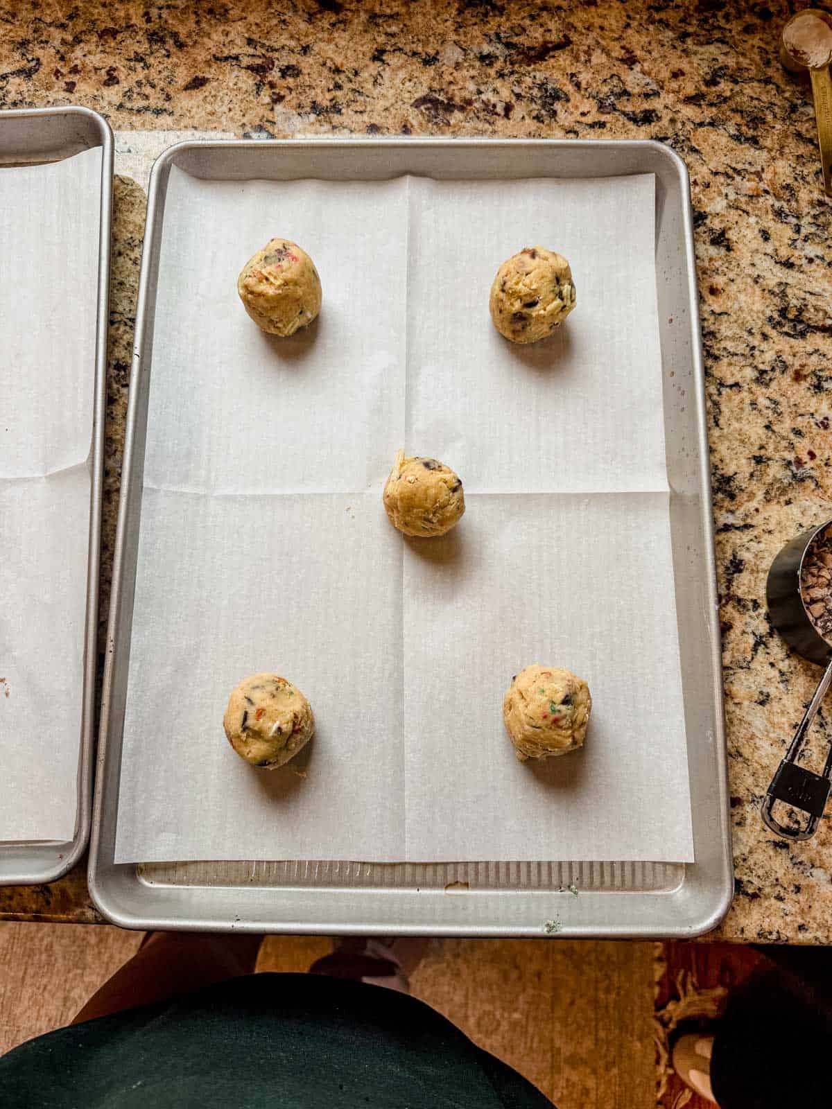 christmas kitchen sink cookie dough roll into balls on a parchment lined baking sheet.