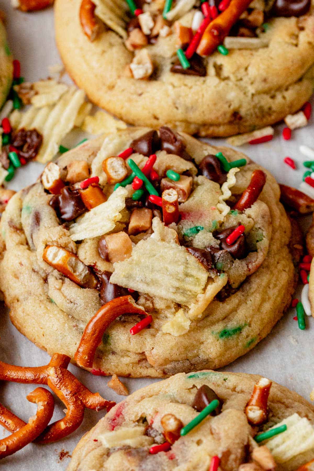 a christmas kitchen sink cookie on parchment paper topped with holiday sprinkles and potato chips.