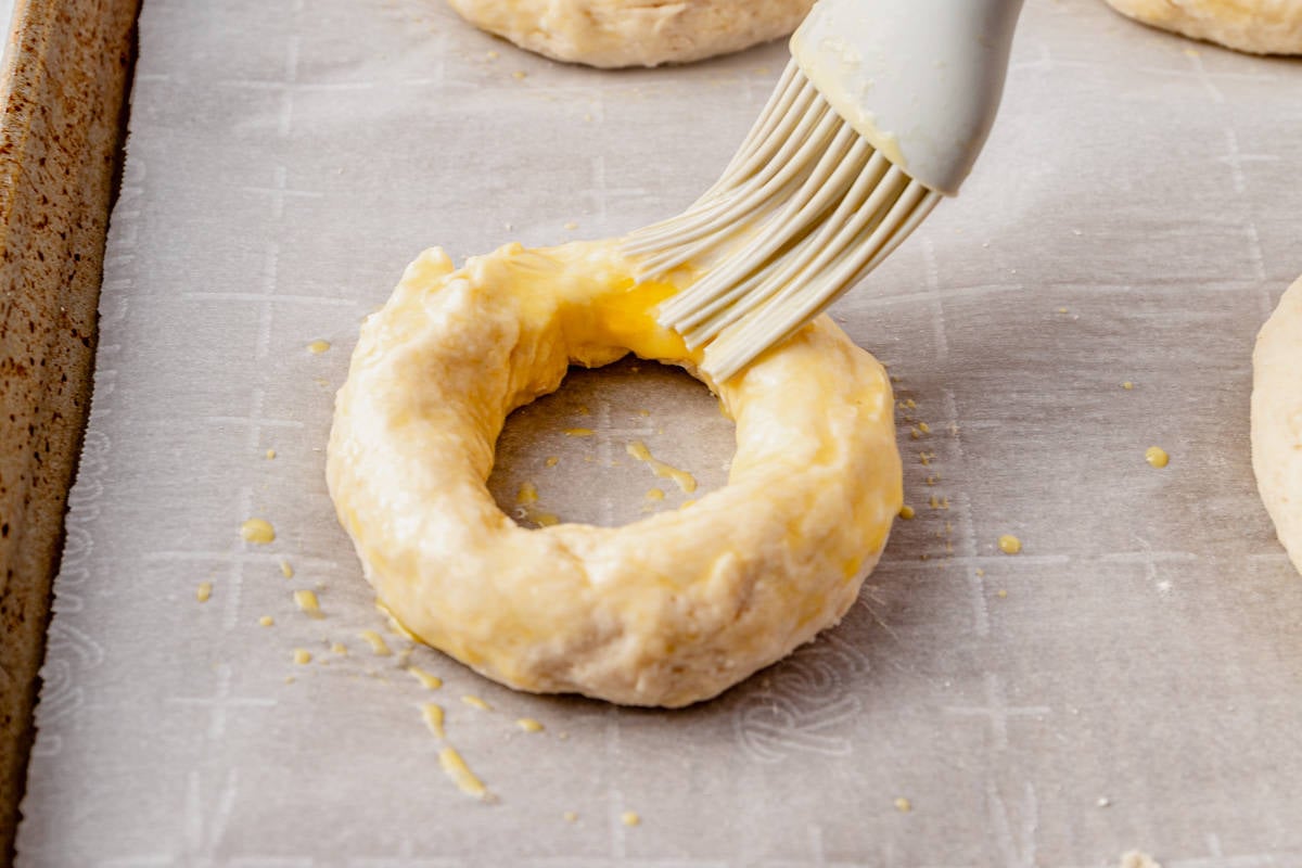 brushing unbaked bagel dough with egg wash 