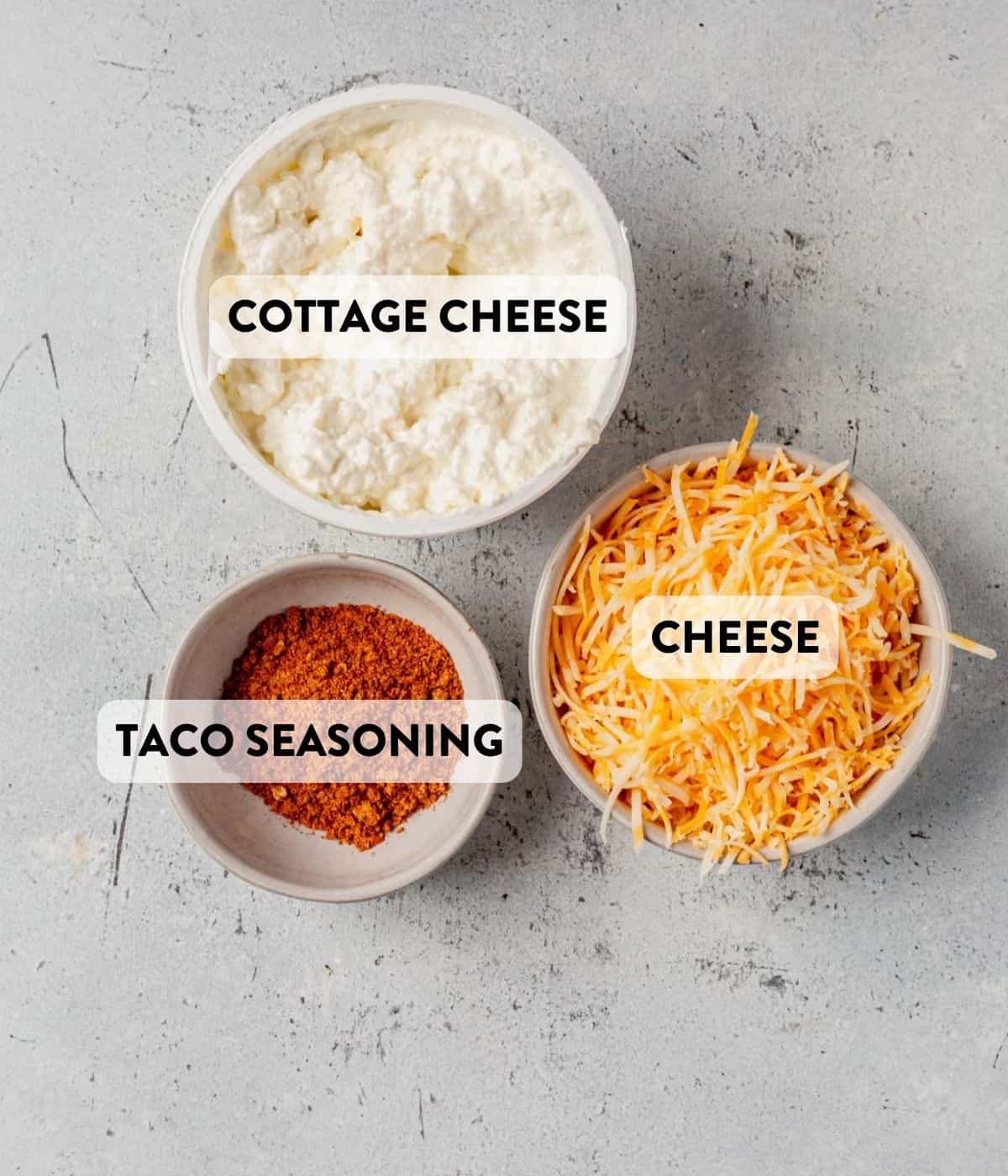 cottage cheese, taco seasoning, and shredded cheese in bowls on a counter