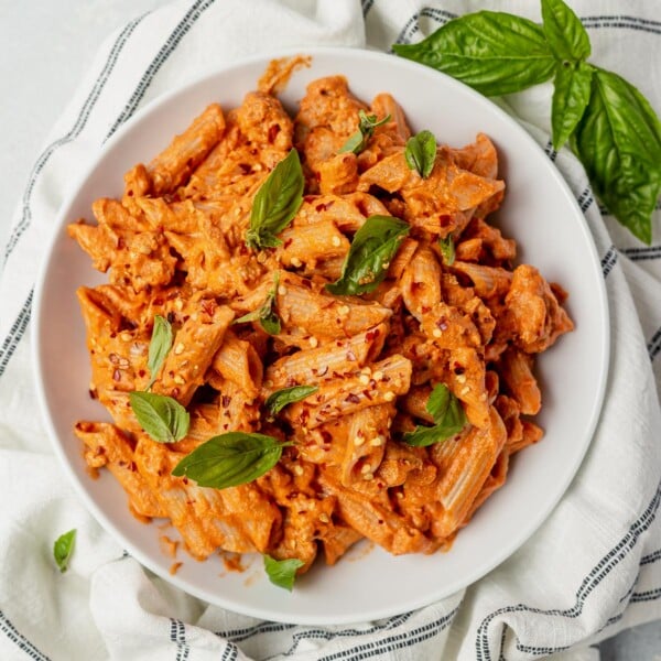 penne arrabbiata on a white plate with fresh basil