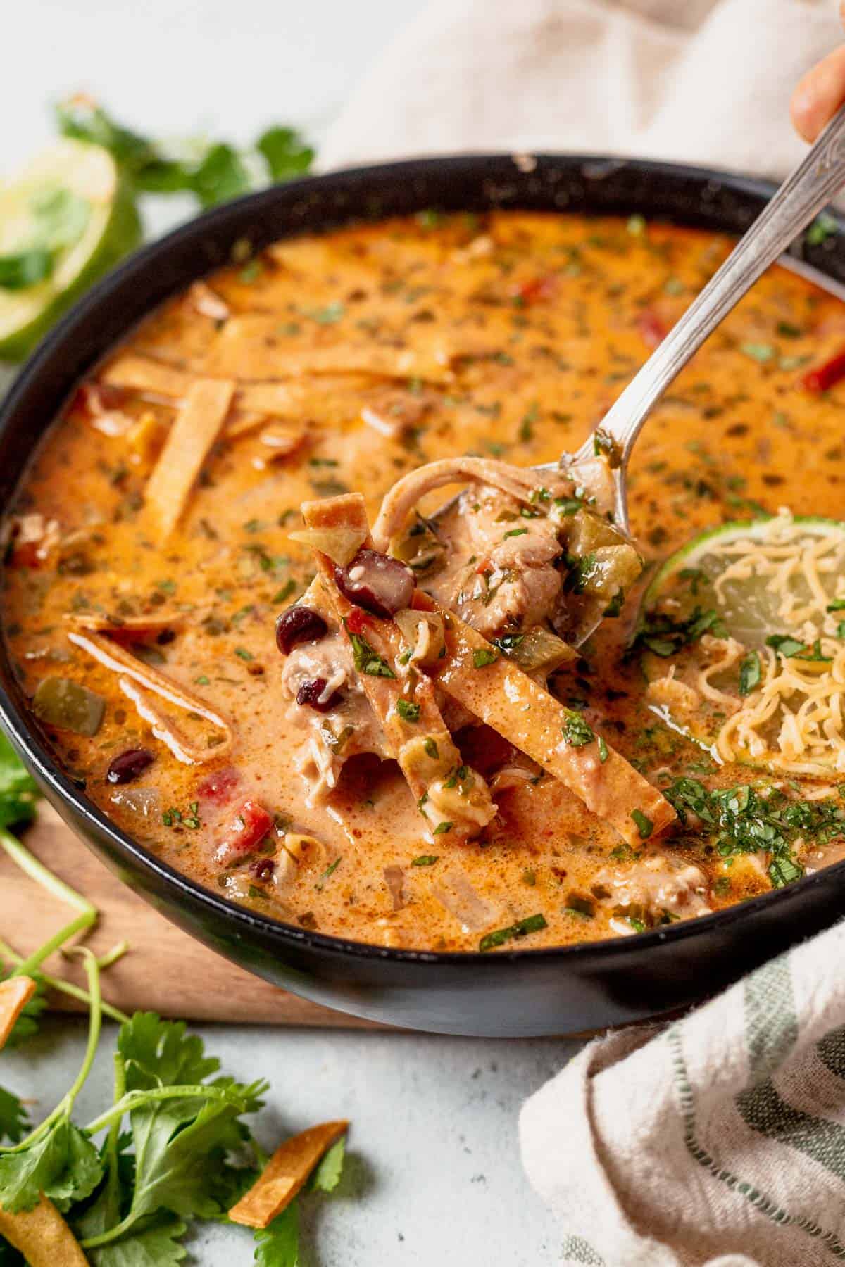 scooping a spoonful of creamy chicken tortilla soup out of a bowl