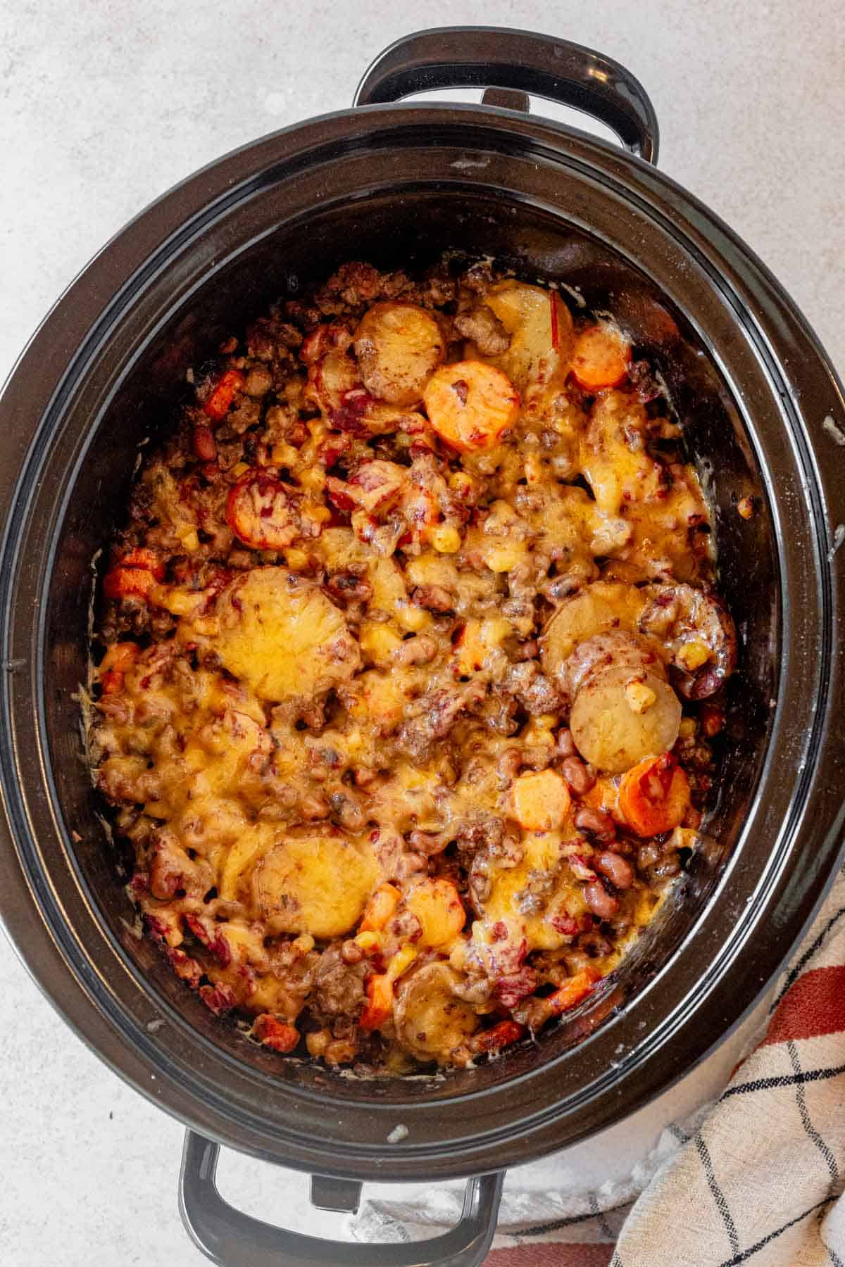 crock pot cowboy casserole cooked and topped with melted cheese.