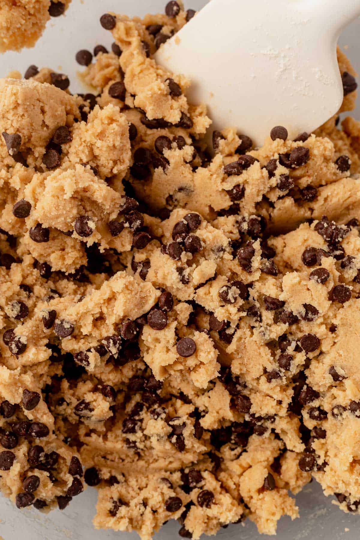 edible cookie dough in a mixing bowl with a rubber spatula