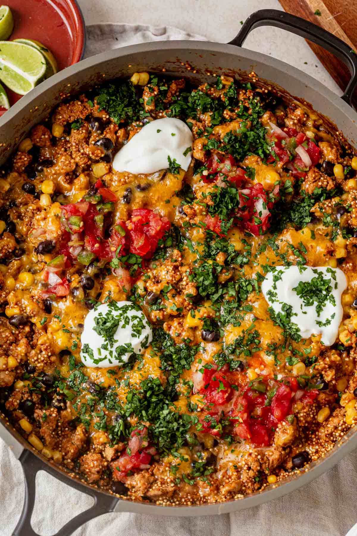 One pan enchilada quinoa skillet topped with sour cream, pico de gallo, and chopped cilantro.