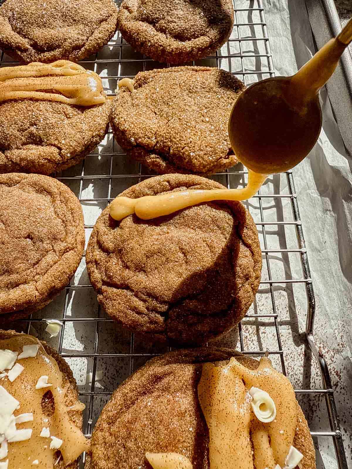 drizzling a brown butter brown sugar glaze on top of a gingerbread latte cookie.