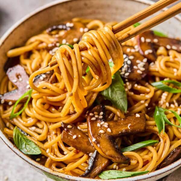 scooping gochujang noodles from a bowl with chopsticks.