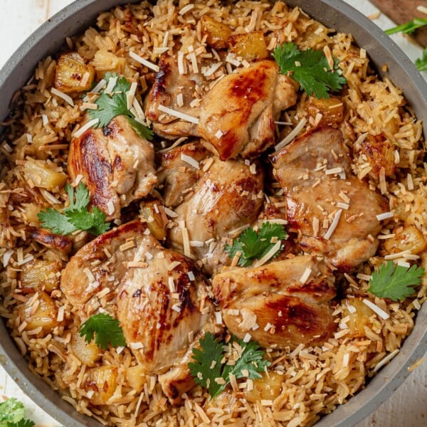 6 hawiian chicken thighs in a skillet with coode basmati rice and topped with toasted coconut and cilantro