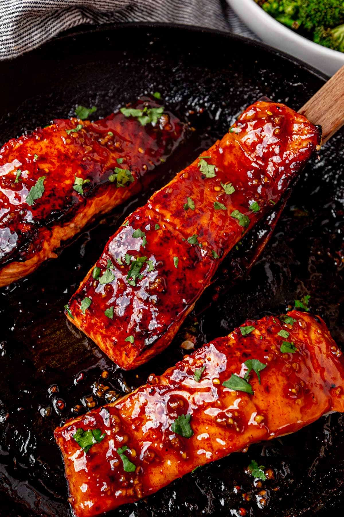 three salmon fillets in a skillet with honey glaze on top