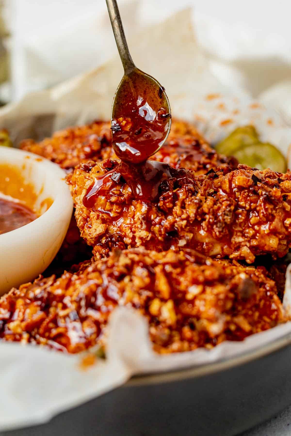 drizzling hot honey sauce on a chicken tender