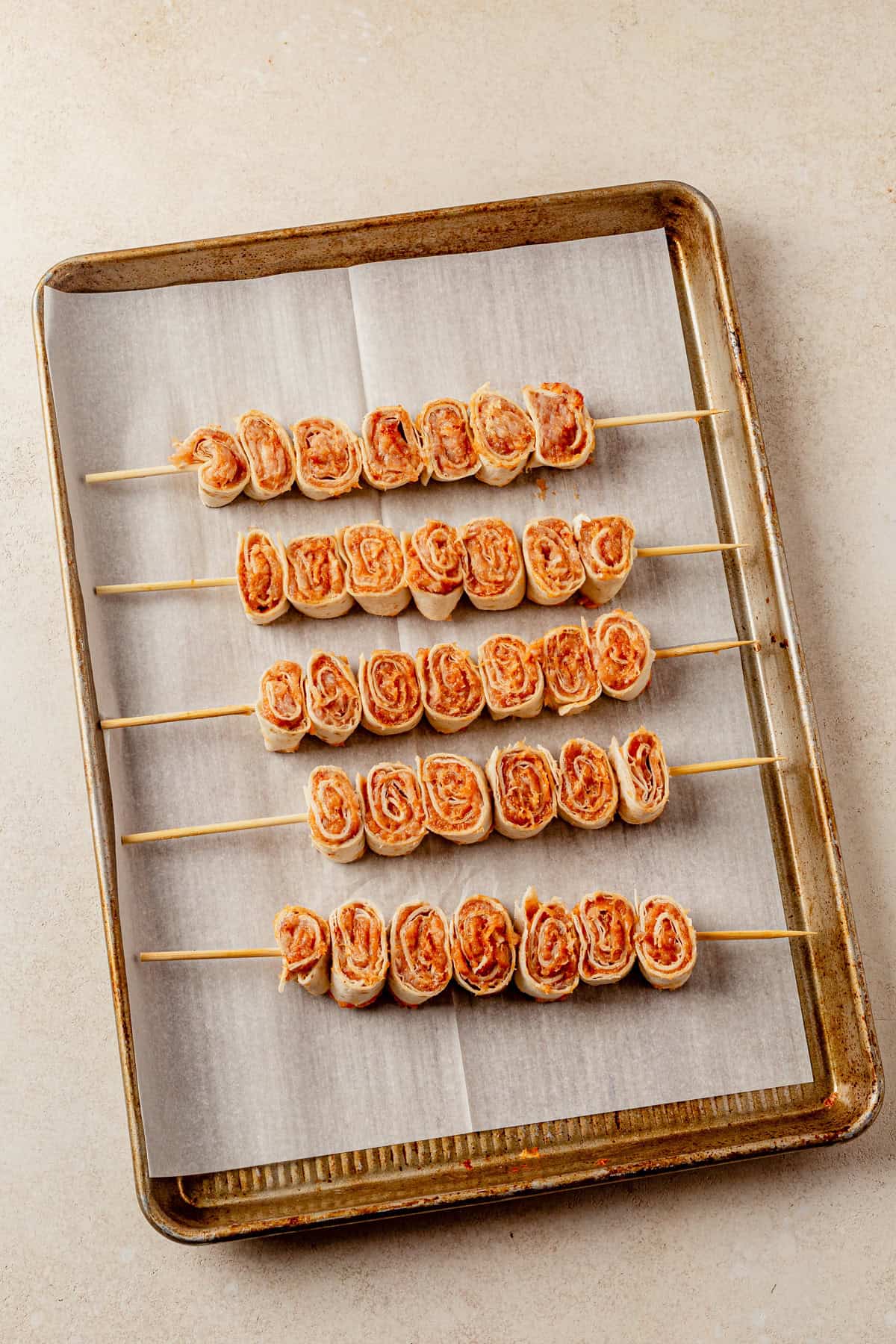 lazy kebab rolls on skewers on a sheet pan before baking.