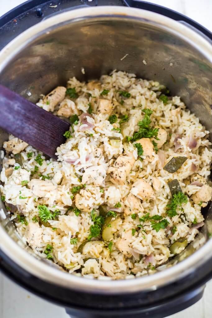 green chicken and rice in the instant pot with a wooden spoon