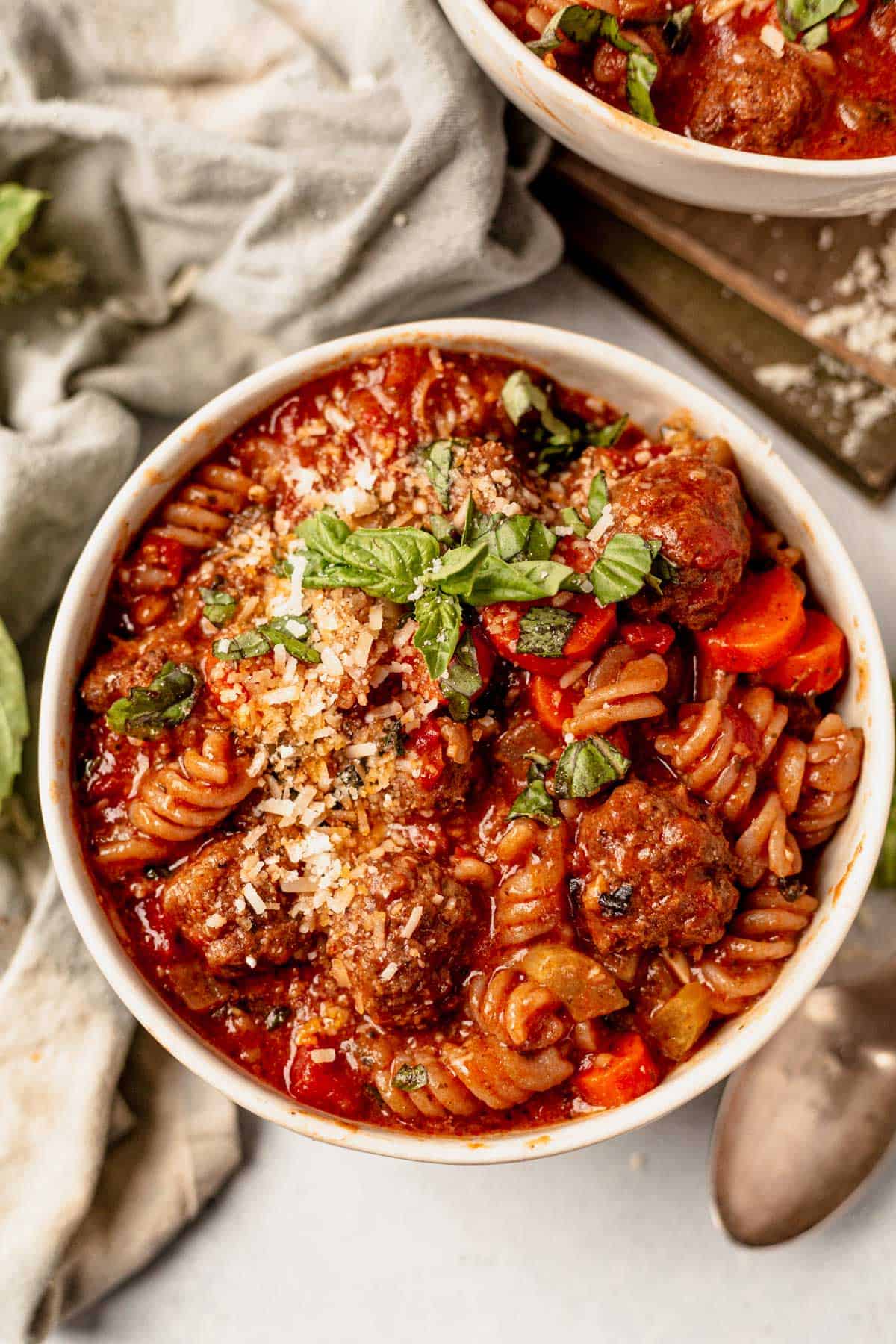 a bowl of italian meatball soup with baked meatballs and noodles in a rich tomato broth.