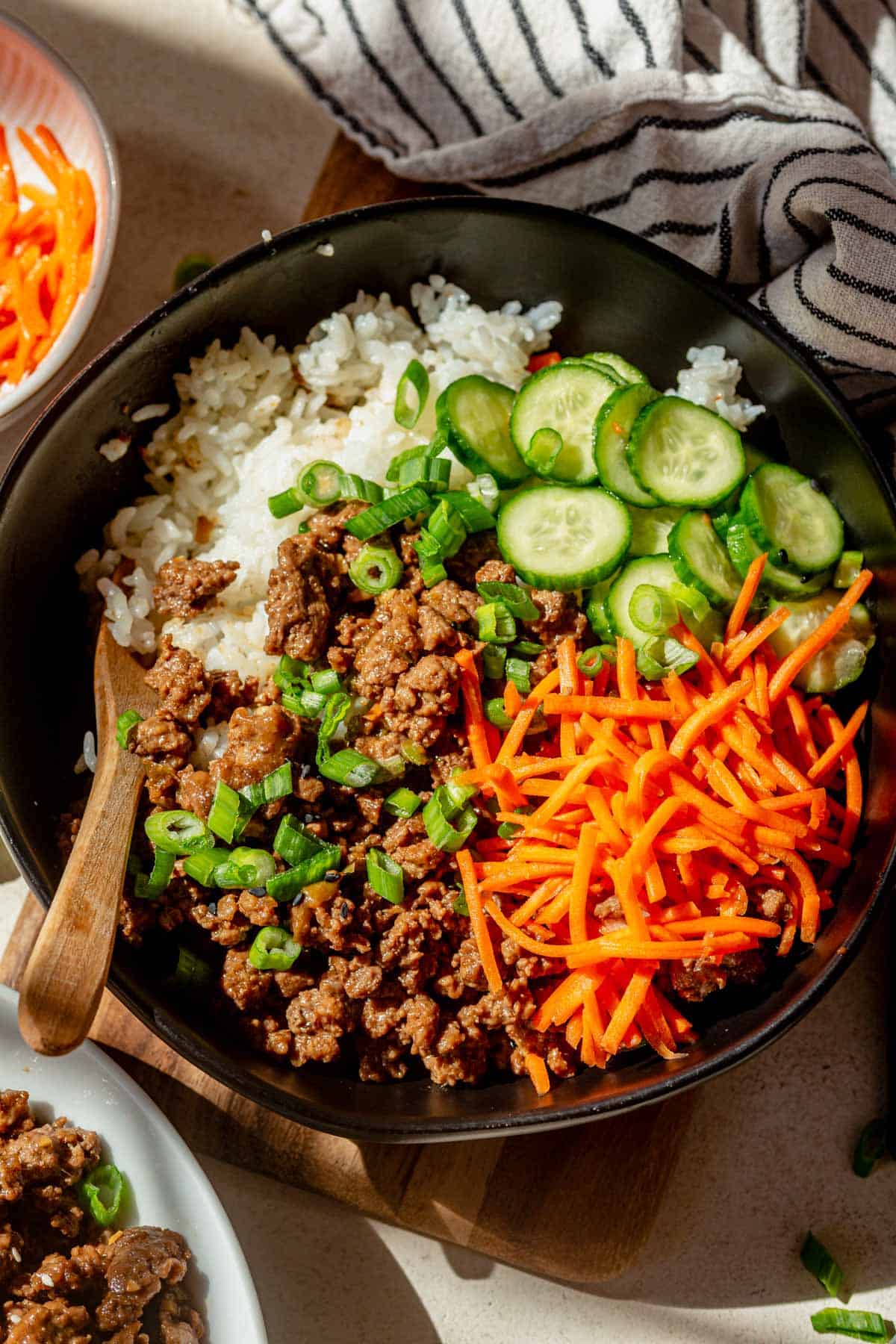 korean ground beef bowls topped with pickled cucumber and carrots.