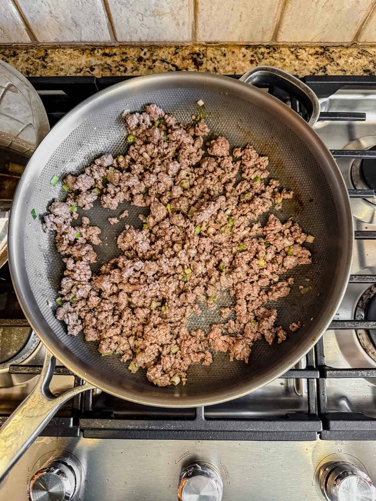 Ground beef cooked in a skillet with ginger, garlic, and green onions.