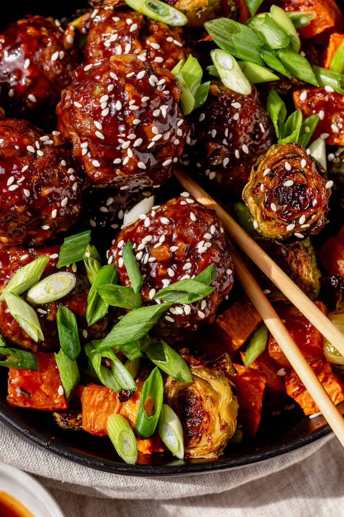 a bowl of korean bbq meatballs with chopticks.