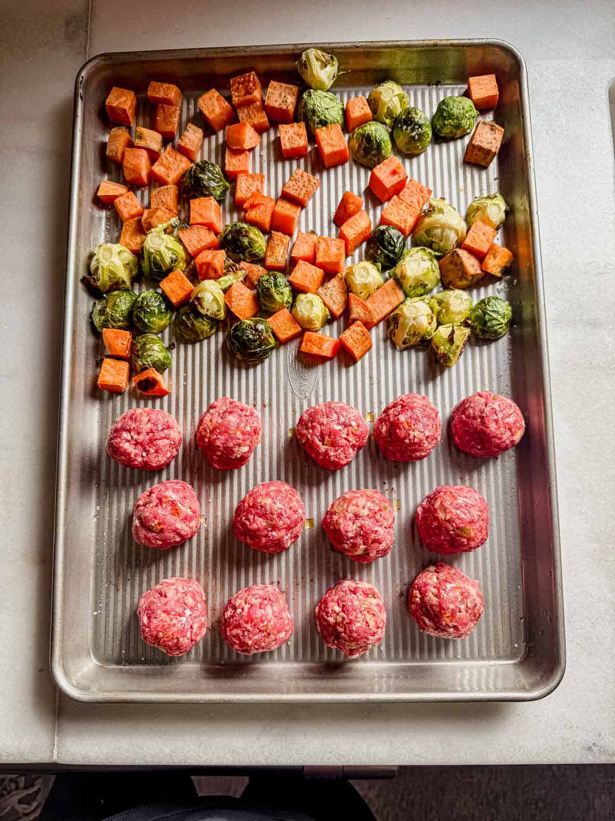 korean meatballs and vegetables on a sheet pan before baking.