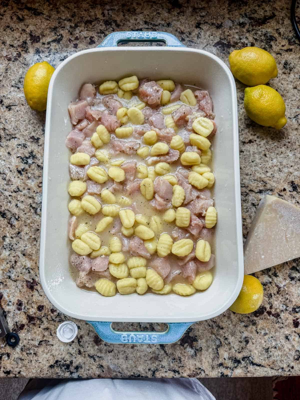 cubed chicken, gnocchi, and chicken broth in a casserole dish.