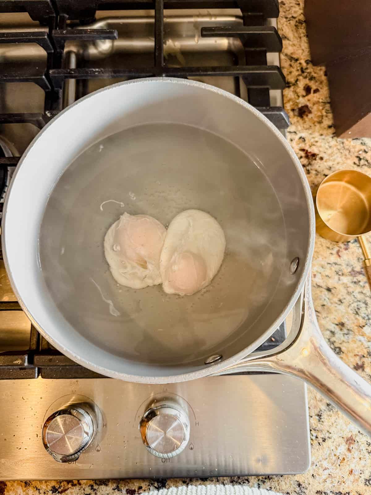 two poached eggs in a pot of steaming water.