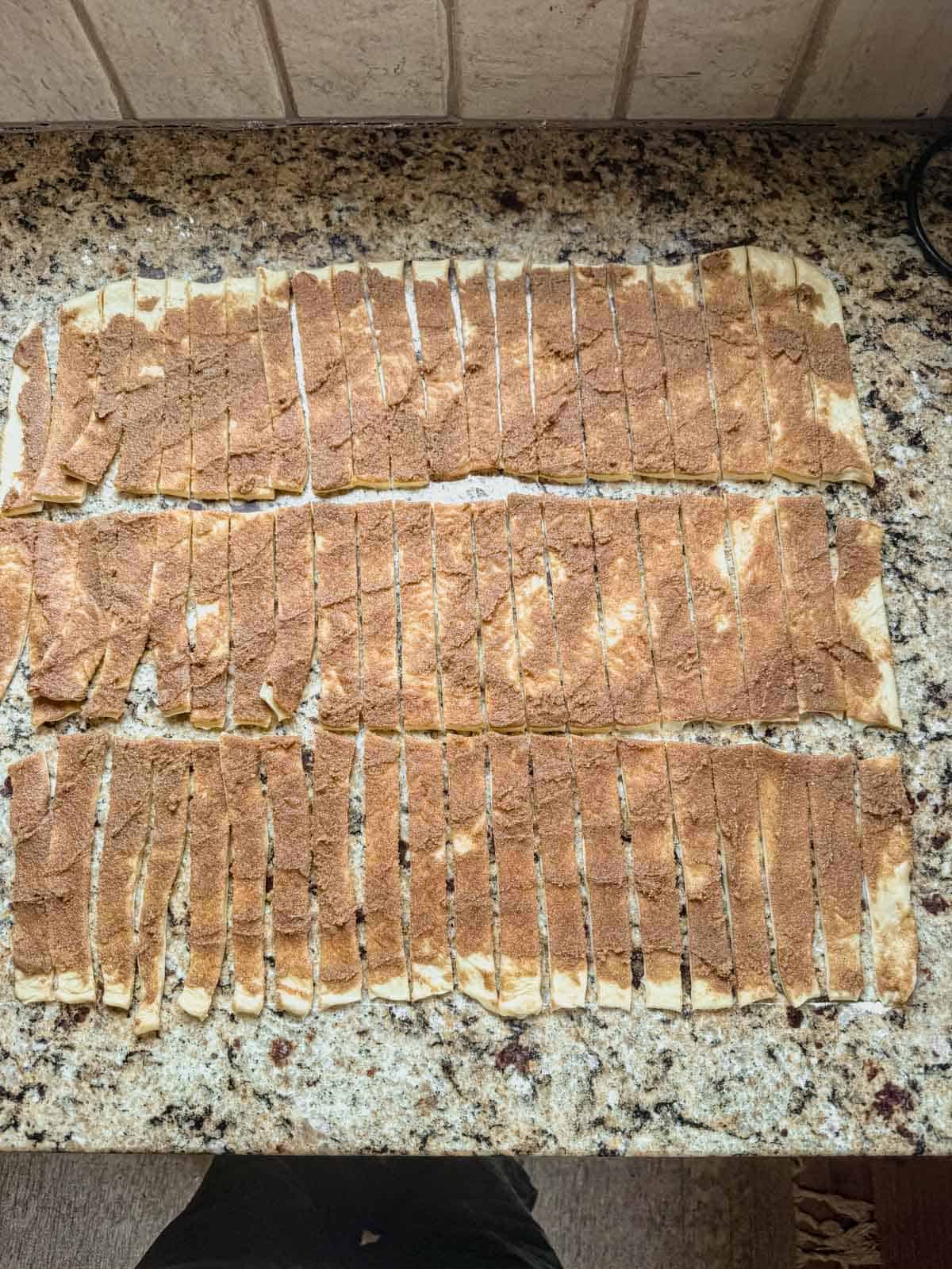 cinnamon roll dough spread out and cut into small strips.