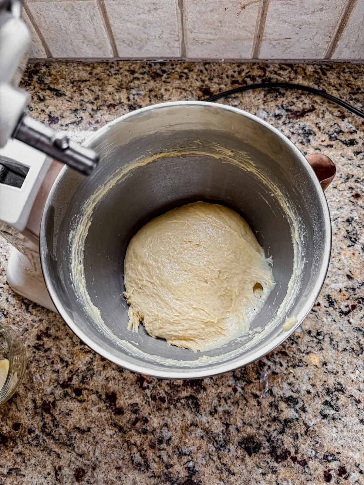 smooth ball of cinnamon roll dough in a stand mixer after kneading.