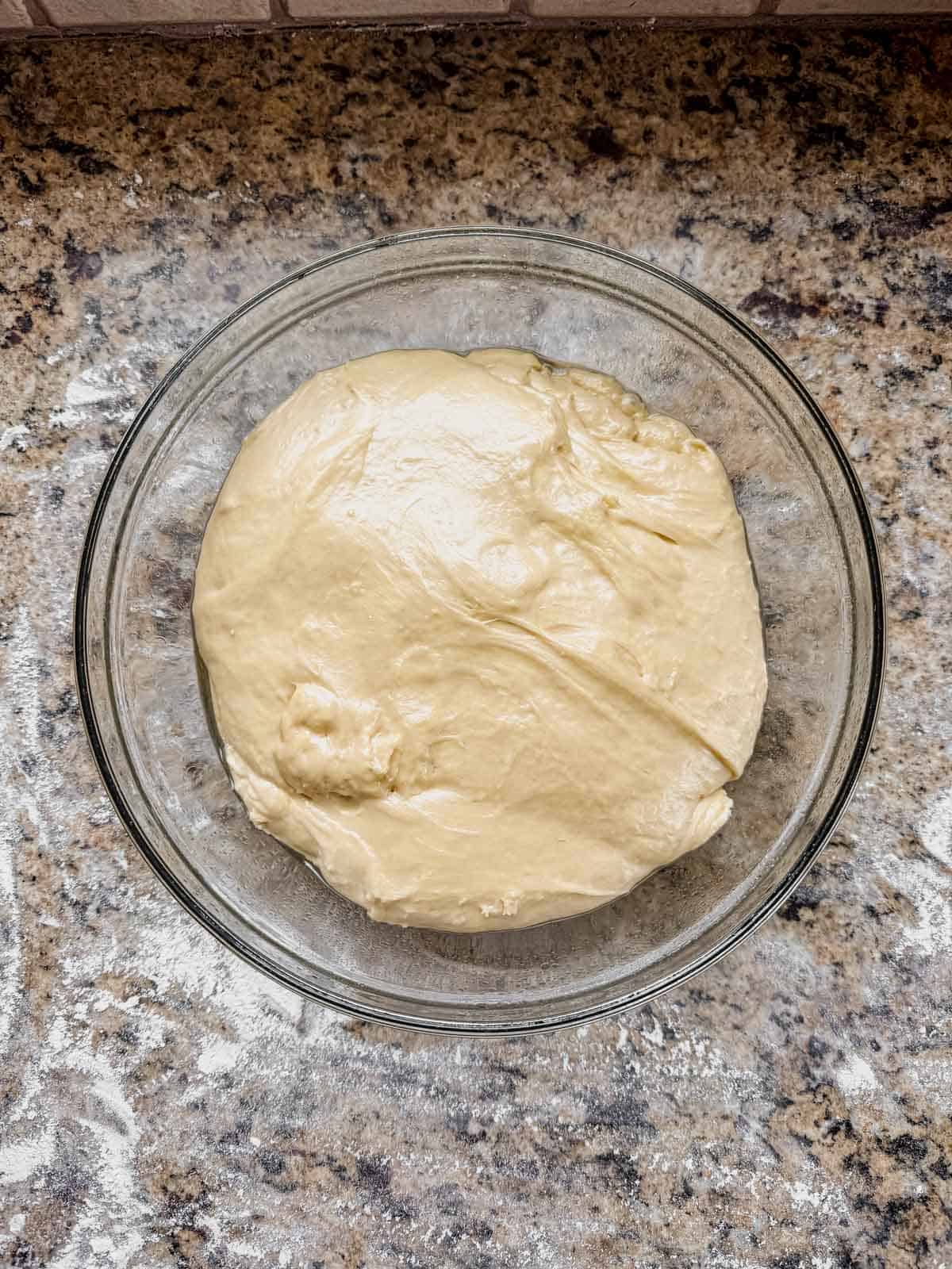 cinnamon roll enriched dough in a greased glass bowl after rising.