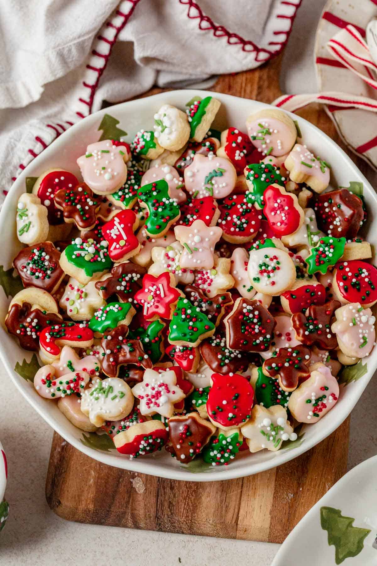 a bowl of mini christmas cookies with icing and sprinkles.