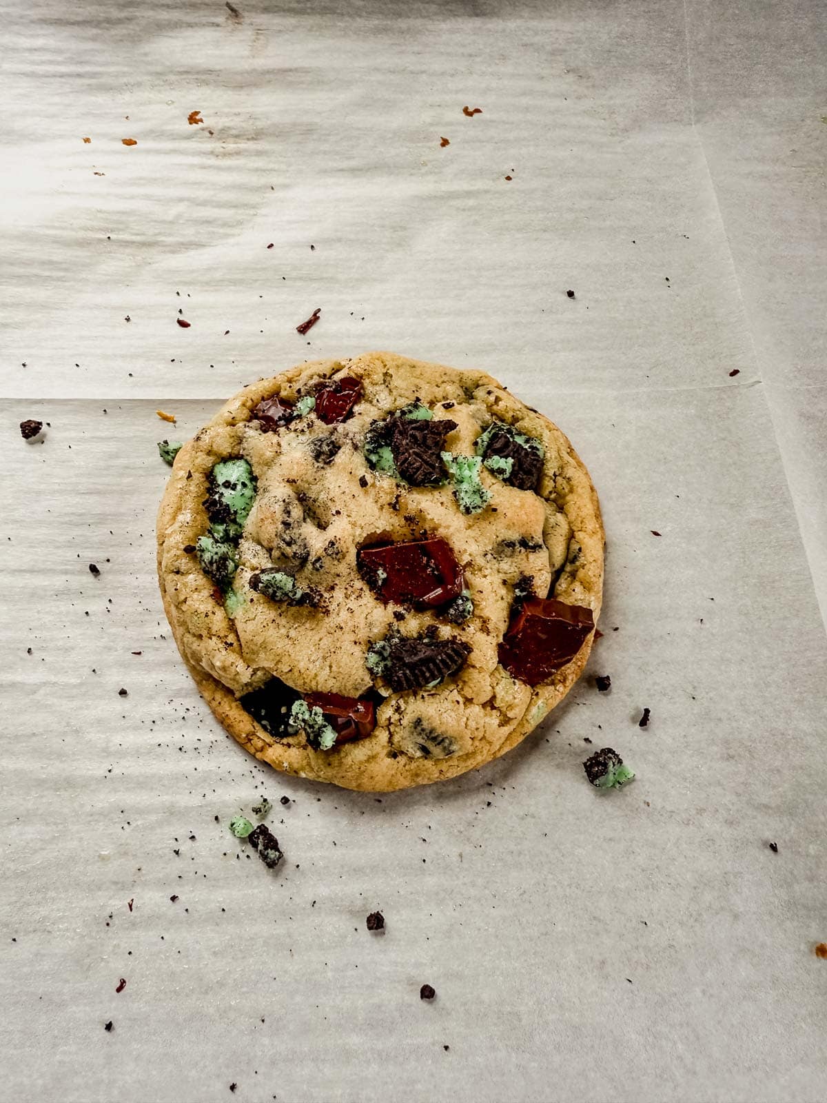 a freshly baked mint oreo cookie cooling on a parchment lined baking sheet.
