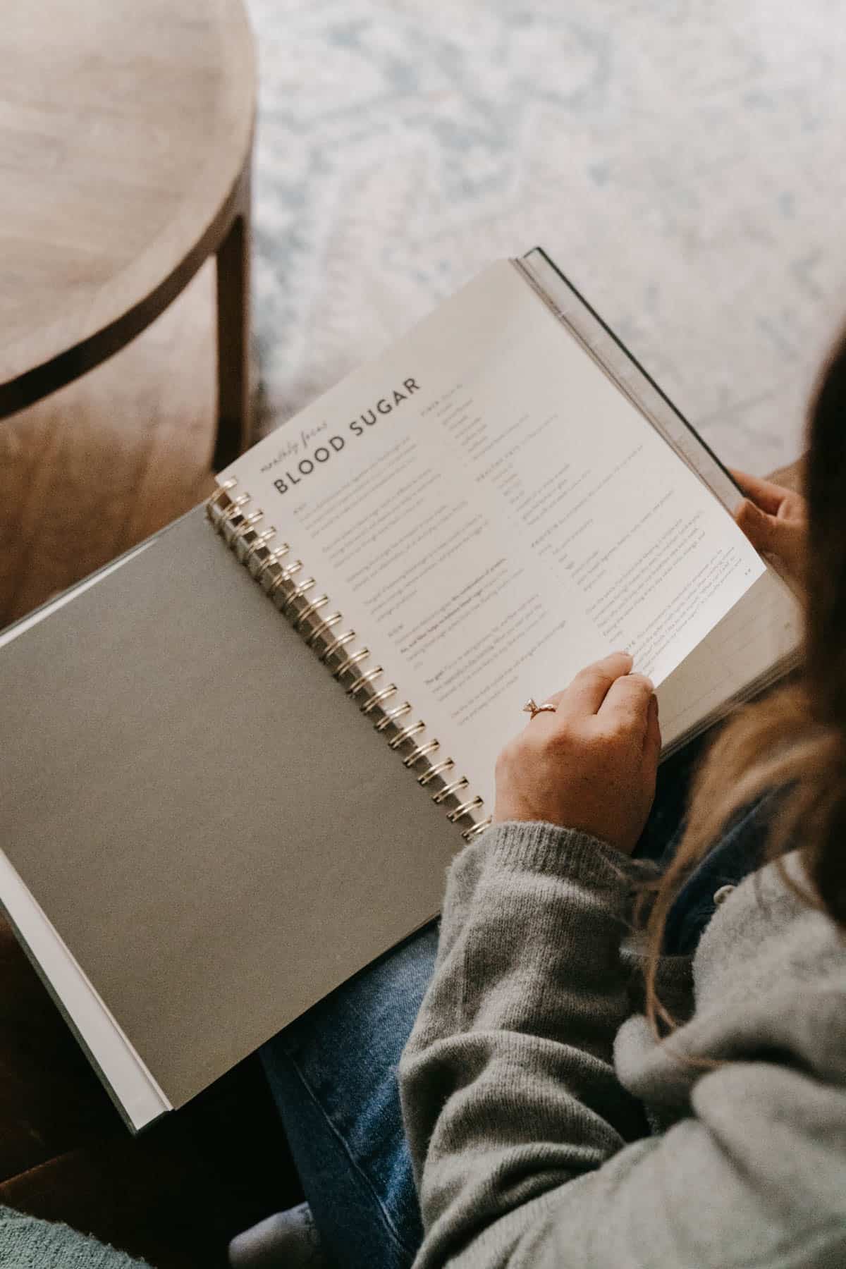 molly thompson holding a pcos planner explaining blood sugar.