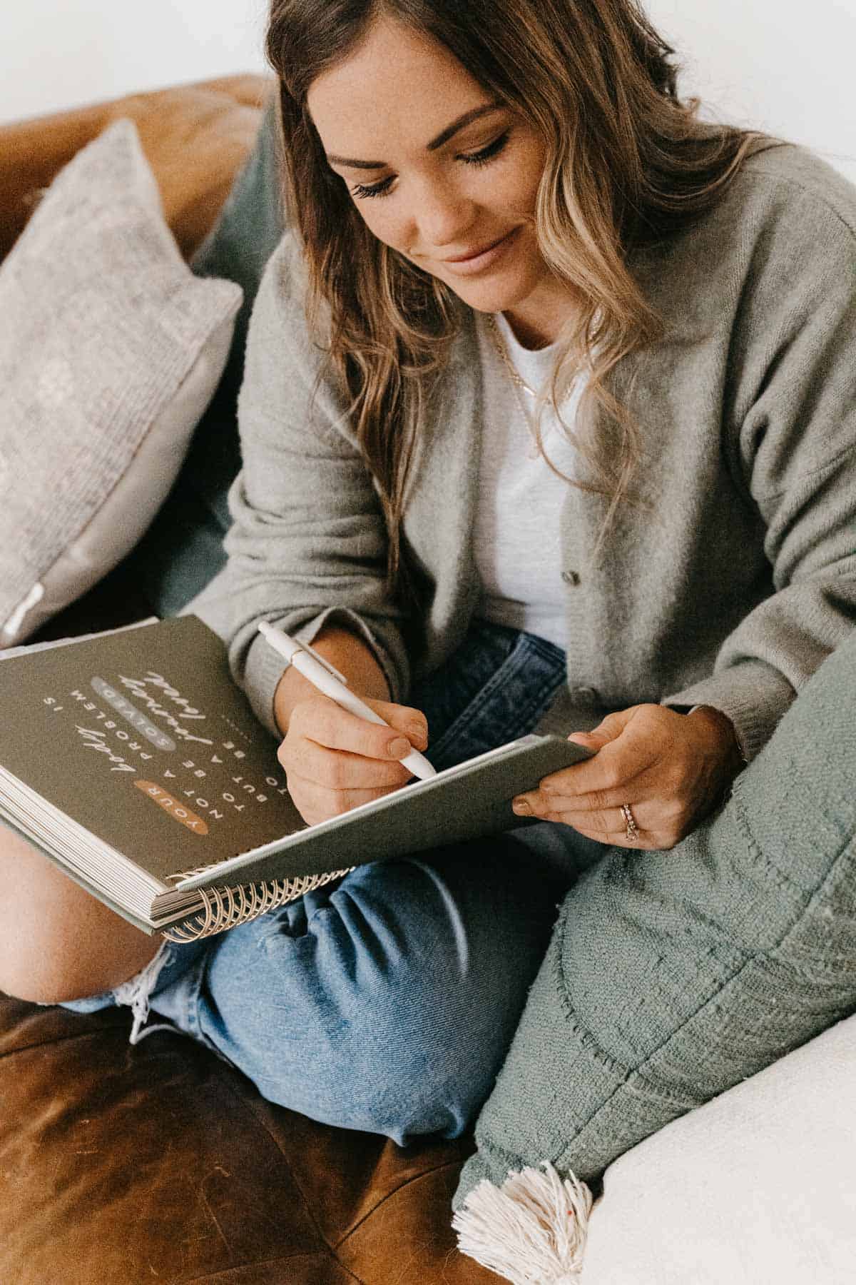 molly writing in her pcos planner sitting on a couch