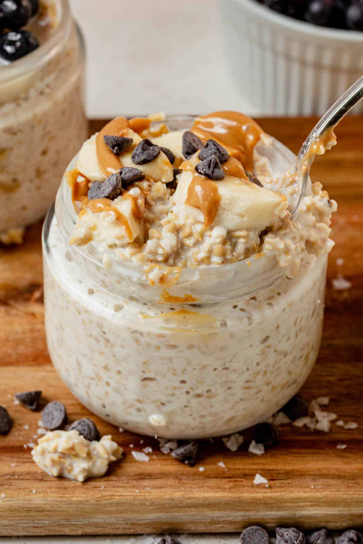 scooping creamy overnight steel cut oats with bananas and peanut butter out of a jar.