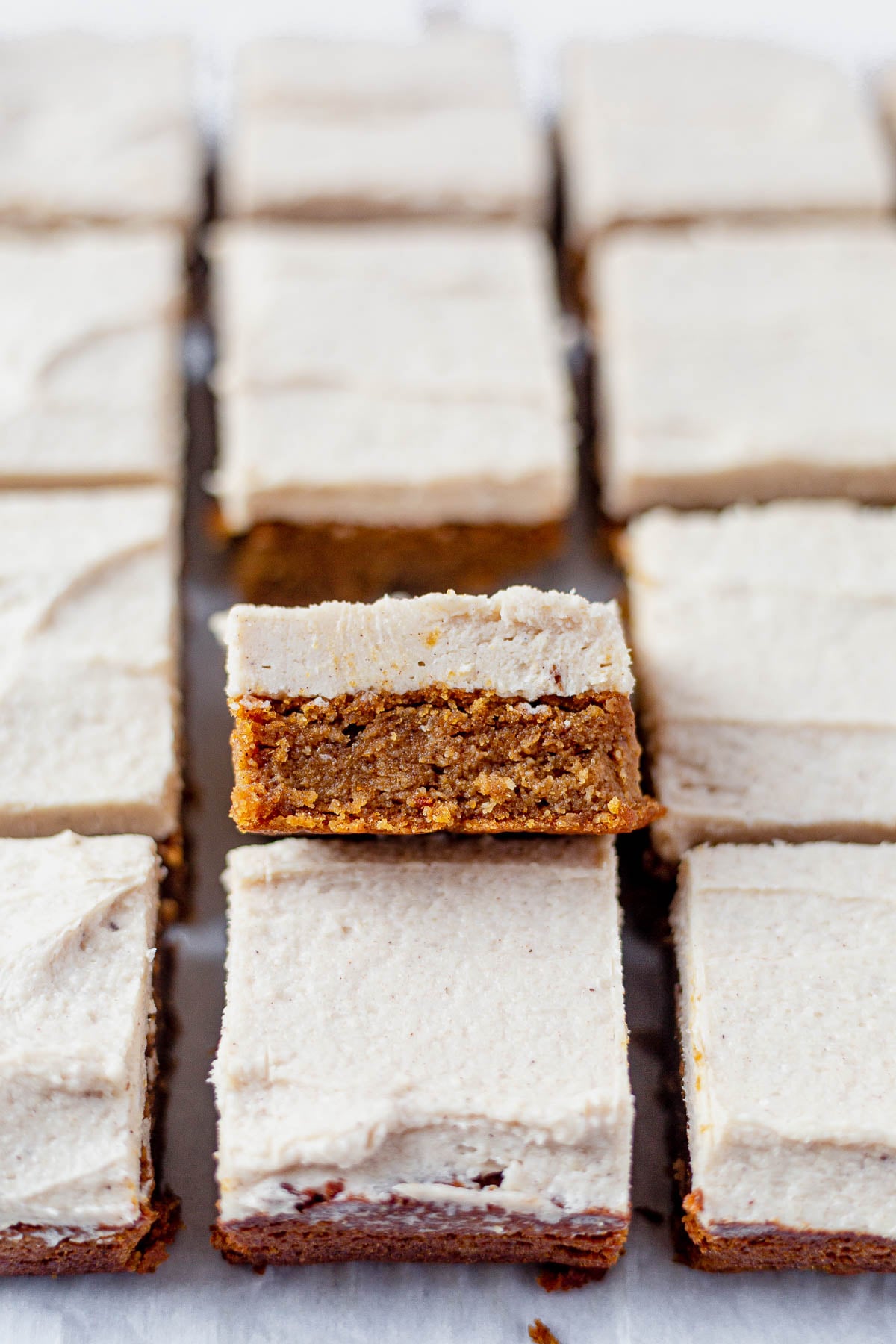 Paleo bars filled with pumpkin and spice! These little squares of heaven taste just like pumpkin pie! And they're paleo:) Which means they're gluten-free, refined sugar free and dairy free. They taste like fall in a bite and are topped with a light maple frosting you will be drooling over. paleo pumpkin bars cut into squares on parchment paper