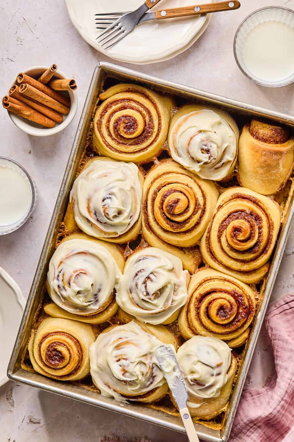 spreading cream cheese frosting on warm cinnamon rolls.