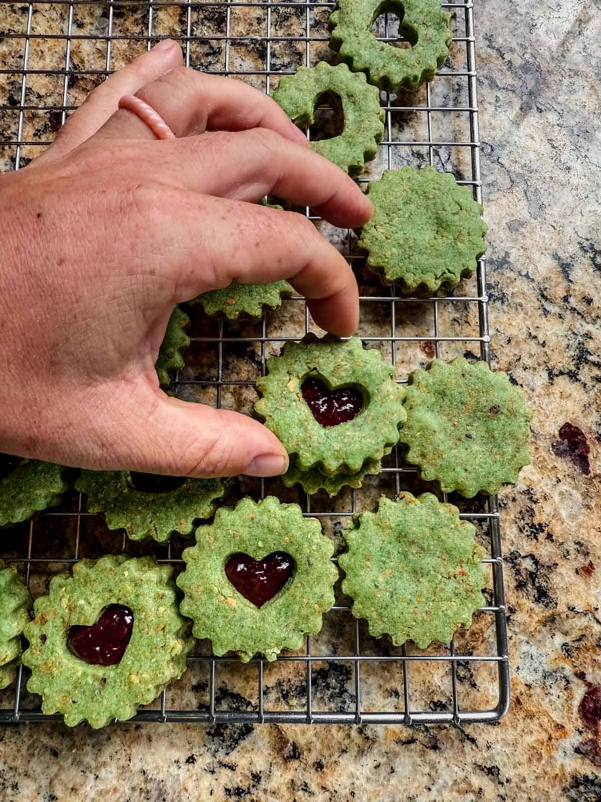 hand assembling the top cookie of a pistachio linzer cookie