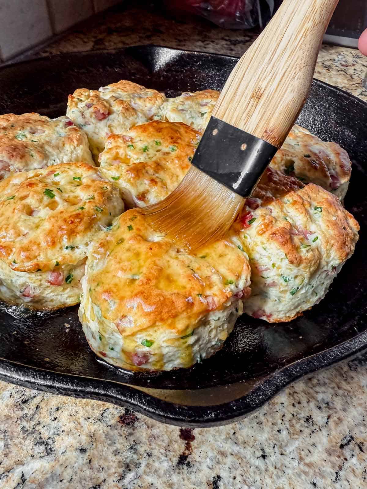 brushing melted honey butter onto a protein biscuit.